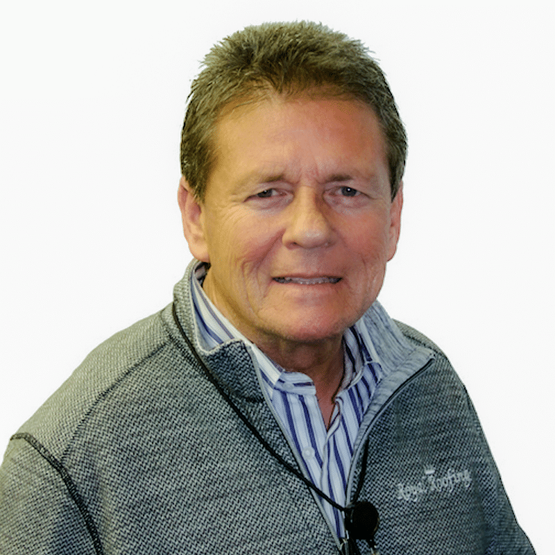 A middle-aged man with short brown hair wearing a gray zip-up sweater over a striped shirt, smiling slightly at the camera against a white background.