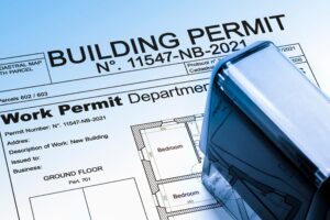 A close-up of a building permit document with a work permit form and floor plan diagram, partially covered by a rubber stamp.